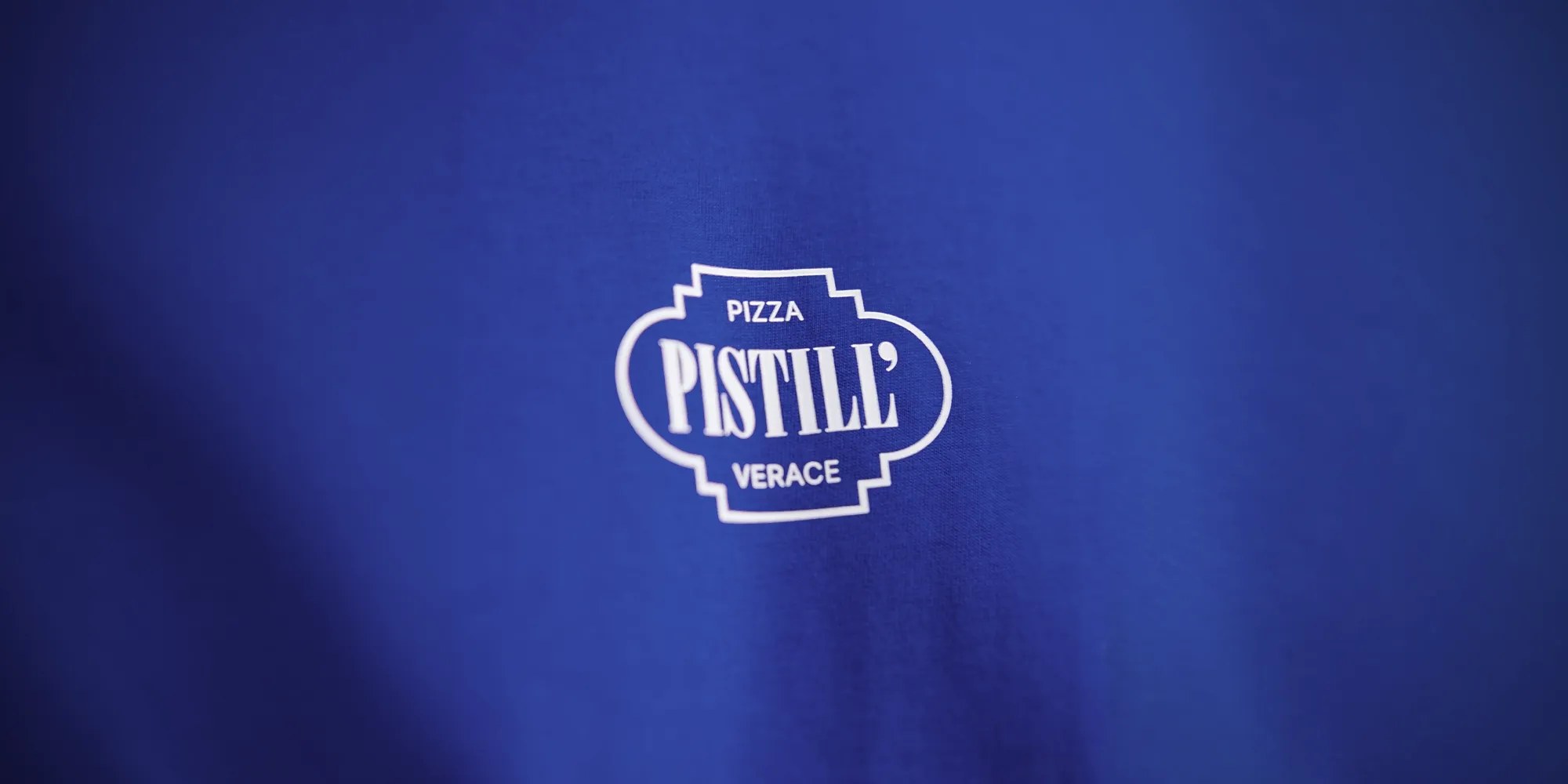 Marchio Pistill' stampato in bianco su tessuto blu: la brand identity della pizzeria verace napoletana